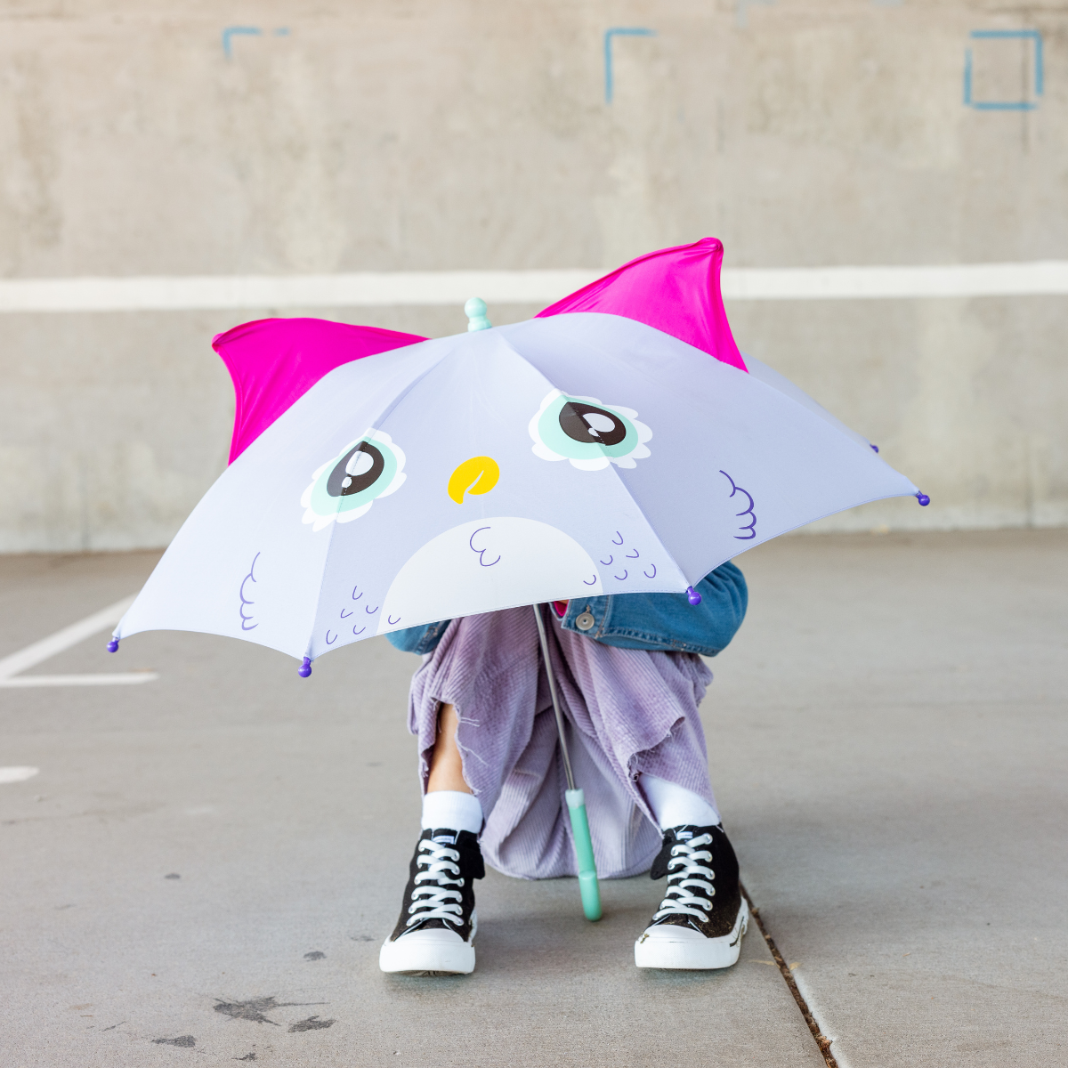 Person holding an owl-themed umbrella in an outdoor setting