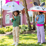 Two children holding umbrellas with animal designs in a garden setting.