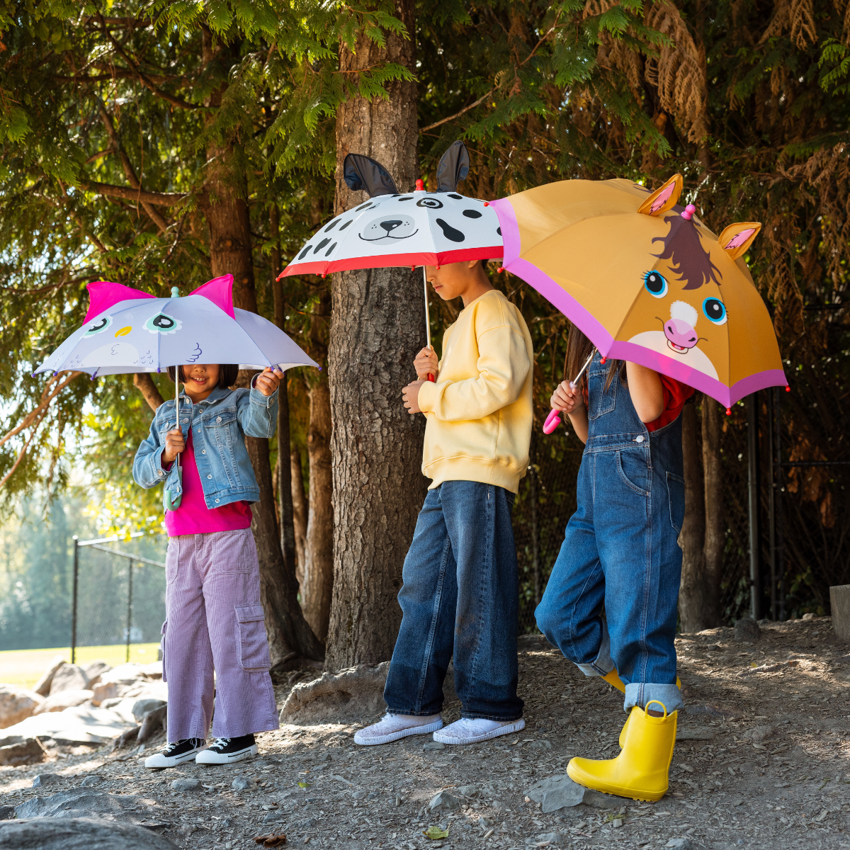 Three children holding animal-themed umbrellas in a forest setting
